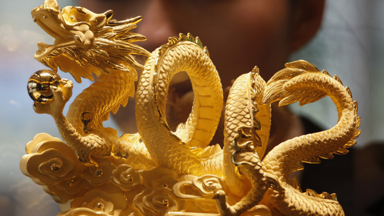 Sales representative poses behind nine-tael 24K gold in shape of dragon forming numerals "2012", symbolizing upcoming Year of the Dragon, at a Chow Tai Fook Jewellery store in Hong Kong